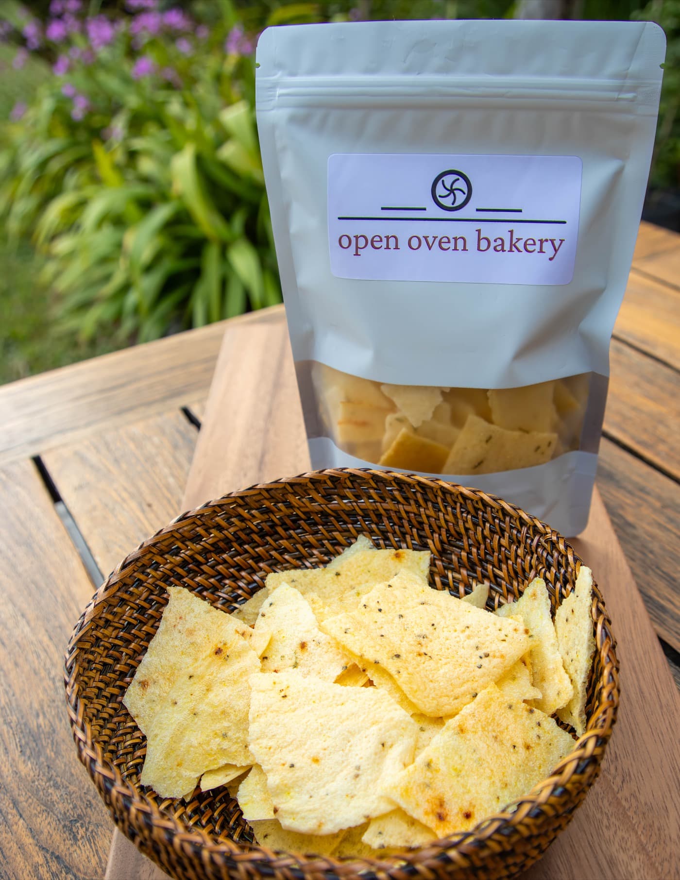 A bag of Open Oven tapioca crackers beside a woven basket piled with crackers